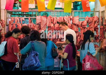 Gli assistenti domestici filipina acquistano carne da un macellaio a WAN Cha marketi, Hong Kong Island Foto Stock