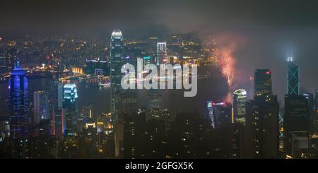 L'alto edificio del Centro sull'Isola di Hong Kong e Tsim Sha Tsui, Kowloon di notte con fuochi d'artificio sul Porto Victoria per celebrare il Capodanno Cinese Foto Stock