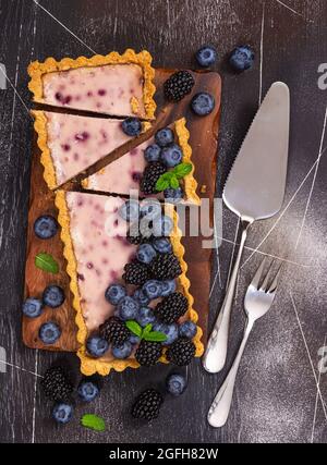 Cheesecake con frutti di bosco freschi, mirtilli e menta su sfondo grigio. Foto Stock