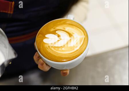 Le mani di un giovane barista che prepara il caffè latte art Foto Stock