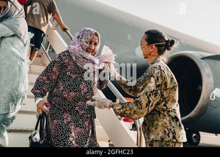 La base aerea navale Sigonella Command Master Chief Anna Wood assiste un evacuatore afghano scendendo da un Extender dell'aeronautica degli Stati Uniti KC-10 alla base aerea navale Sigonella, 22 agosto 2021. NAS Sigonella sta attualmente sostenendo la missione del Dipartimento della Difesa per facilitare la partenza e il trasferimento in sicurezza dei cittadini statunitensi, dei beneficiari di visti speciali per l'immigrazione e delle popolazioni afghane vulnerabili provenienti dall'Afghanistan. La Sigonellas posizione strategica di NAS consente alle forze degli Stati Uniti, alleate e partner di schierarsi e rispondere come richiesto per garantire la sicurezza e la stabilità in Europa, Africa e C centrale Foto Stock