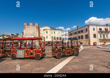 Piccolo trenino turistico rosso nel paese di Bardolino per un giro turistico nella cittadina sulla costa del Lago di Garda. Verona, Italia. Foto Stock