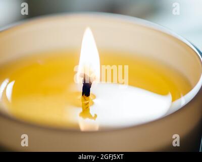 Candela che brucia stoppino con cera beige primo piano su uno sfondo chiaro. Candela Wick fiamma, estrema foto da vicino con spazio copia Foto Stock