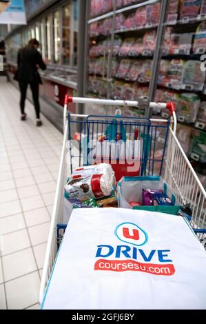 Super U supermercato: Donna, commissionatore / imballatore selezione dei prodotti in una sezione del supermercato utilizzando un dispositivo mobile per controllare la registrazione del cliente Foto Stock