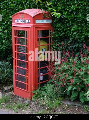 Un ex telefono rosso ora convertito in un defibrillatore in un angolo rurale del Derbyshire. Foto Stock