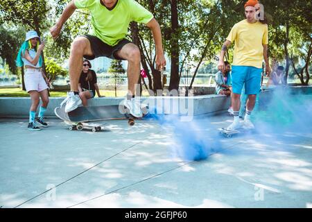 pattinatori con bombe fumanti colorate. Gli skateboarder professionisti si divertono allo skate Park Foto Stock