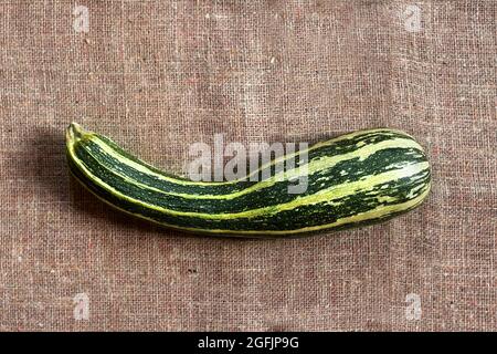 Zucchine fresche a righe su sfondo di sackcloth con spazio per la copia. Disposizione piatta, vista dall'alto. Stile rustico Foto Stock