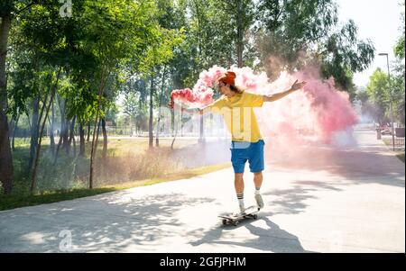 Pattinatori con bombe fumanti colorate. Gli skateboarder professionisti si divertono allo skate Park Foto Stock