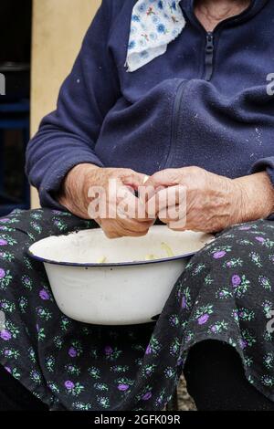 primo piano mani di una donna anziana che prepara fagioli verdi per cucinare Foto Stock