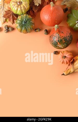 Composizione verticale festosa di zucche, foglie colorate su sfondo arancione con spazio per il testo. Giorno di ringraziamento e modello di Halloween. Foto Stock