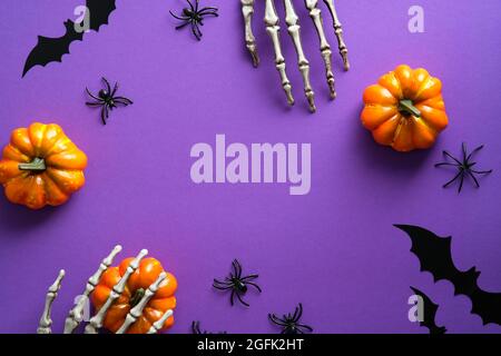 Decorazioni di Halloween, zucche, ragni, pipistrelli su sfondo viola. Disposizione piatta, vista dall'alto, spazio di copia. Halloween biglietto d'auguri mockup. Foto Stock