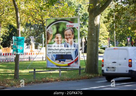 Wiesbaden, Germania - 25 agosto 2021: Il tabellone della campagna elettorale dell'Unione tedesca Christlich Demokratische (CDU) nel centro della città di Wiesbaden, Hessen. L'Unione Democratica cristiana (CDU) è un partito politico cristiano-democratico e liberal-conservatore in Germania ed è guidato da Armin Laschet. La Germania si trova di fronte alle elezioni federali del 26 settembre. Alcuni utenti della strada in background Foto Stock