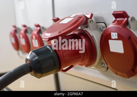 Prese industriali e spina sul quadro di distribuzione. Elettricità per cantiere, fornitura temporanea di energia Foto Stock