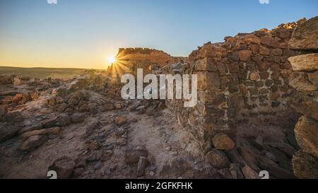 Vecchio muro sulla cima di una montagna rocciosa durante il tramonto a Taghit, Algeria Foto Stock