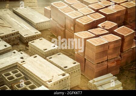 Tombini prefabbricati in calcestruzzo e altri materiali da costruzione immagazzinati in un cantiere Foto Stock