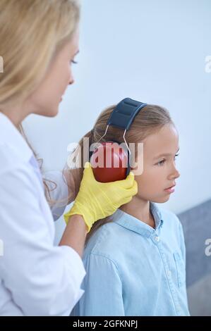 Ragazza che è preparata per un test uditivo da un medico Foto Stock