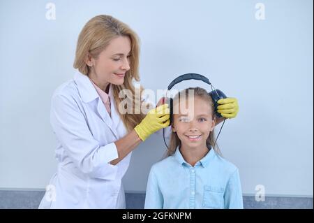 Medico che prepara un giovane paziente per un test audiometrico Foto Stock