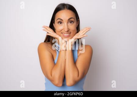 Stupito giovane donna bruna in abito casual estremamente felice, con occhi aperti e bocca, in piedi su sfondo bianco Foto Stock