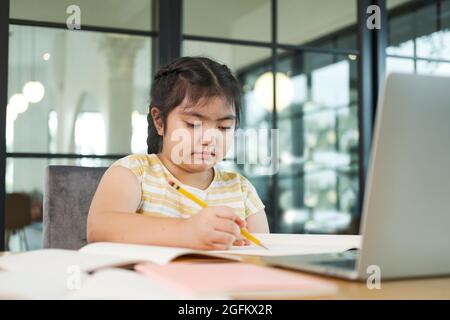 Bambina bambini che usano un computer portatile, studiando attraverso online. Foto Stock