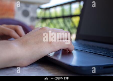 Donna freelance che lavora sul balcone della sua casa utilizzando il laptop. Donna seduta su sedia e utilizzando il computer all'aperto. Foto Stock