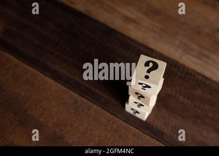 Cubo di legno impilato con punto interrogativo sul tavolo. Concetto di FAQ, domande, incertezza e indovinello Foto Stock