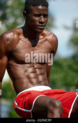 Giovane atletico che fa push-up. Modello di fitness che fa l'allenamento all'aperto. Un ragazzo forte e muscolare che si esercita Foto Stock
