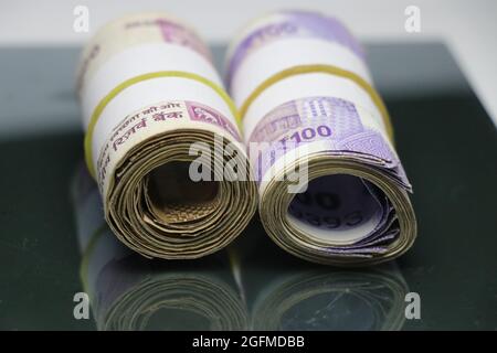 Rotoli di banconote indiane e messi su un tavolo di vetro Foto Stock