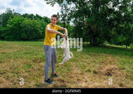 Il giovane caucasico cammina e allena il suo cane Jack Russell terrier nel parco Foto Stock