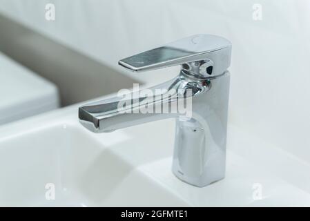 Lavello rettangolare in marmo bianco con moderno bacino overlay e rubinetto in acciaio inossidabile lucido. Aprire l'acqua di sgushing del rubinetto. Foto Stock