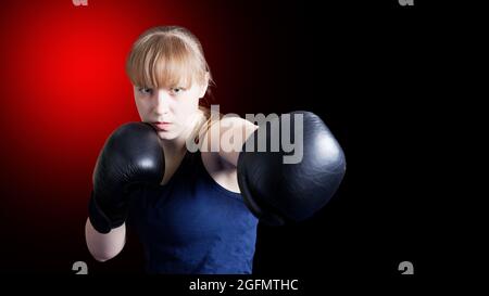 Ragazza sportiva che fa esercizi di boxe, facendo diretto colpito isolato su sfondo nero Witn rosso spot. CopySpace. Foto Stock