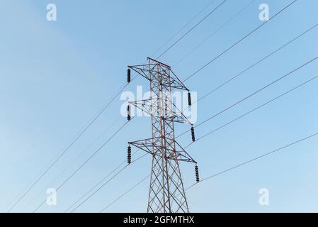 Linee elettriche ad alta tensione pilone di trasmissione dell'elettricità su sfondo blu cielo. Parte della sottostazione ad alta tensione con interruttori e sezionatori elettrici Foto Stock