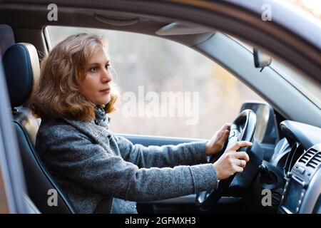 Ritratto di una donna seduta al volante di un'auto. Messa a fuoco superficiale. Foto Stock