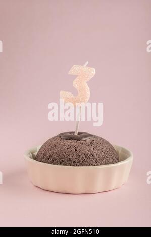 Una piccola torta di compleanno con l'età della candela tre su rosa Foto Stock