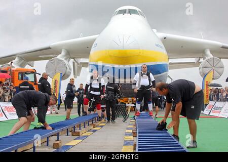 Hostomel, Ucraina. 26 agosto 2021. HOSTOMEL, UCRAINA - 26 AGOSTO 2021 - otto uomini forti sono raffigurati durante un tentativo di tirare Antonov an-225 Mriya, l'aereo più pesante mai costruito, Nel tentativo di stabilire il record per segnare 30 anni di indipendenza dell'Ucraina e il 75° anniversario della Società Antonov presso l'aerodromo Antonov, Hostomel, Regione di Kiev, Ucraina settentrionale. Gli atleti hanno tirato l'aereo 285t per quattro metri e 30 centimetri in un minuto e 13 secondi. Credit: Ukrinform/Alamy Live News Foto Stock