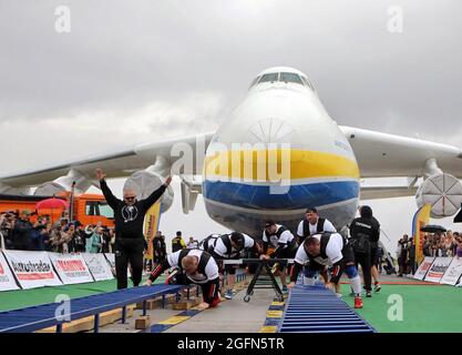 Hostomel, Ucraina. 26 agosto 2021. HOSTOMEL, UCRAINA - 26 AGOSTO 2021 - otto uomini forti sono raffigurati durante un tentativo di tirare Antonov an-225 Mriya, l'aereo più pesante mai costruito, Nel tentativo di stabilire il record per segnare 30 anni di indipendenza dell'Ucraina e il 75° anniversario della Società Antonov presso l'aerodromo Antonov, Hostomel, Regione di Kiev, Ucraina settentrionale. Gli atleti hanno tirato l'aereo 285t per quattro metri e 30 centimetri in un minuto e 13 secondi. Credit: Ukrinform/Alamy Live News Foto Stock