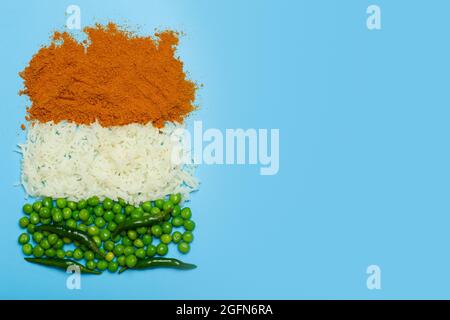 Bandiera indiana fatta da sfondo di cibo. Riso basmati, curry, piselli verdi e peperoncini nei colori della bandiera indiana su sfondo blu. Foto di alta qualità Foto Stock