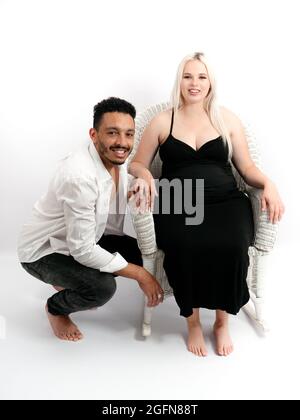 Ritratto verticale di una coppia multietnica elegante e felice in attesa di un bambino Foto Stock