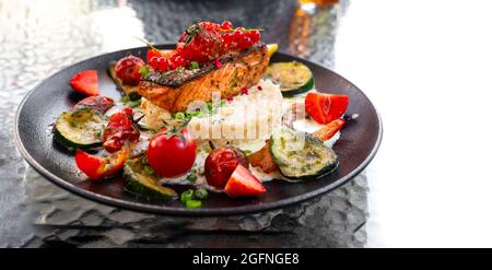Delizioso risotto con bistecca di salmone alla griglia al forno con frutti di bosco e verdure. Cucina mediterranea Foto Stock