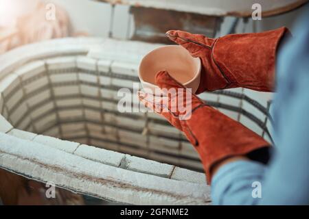 Vasaio femmina che spara ceramica in forno elettrico Foto Stock