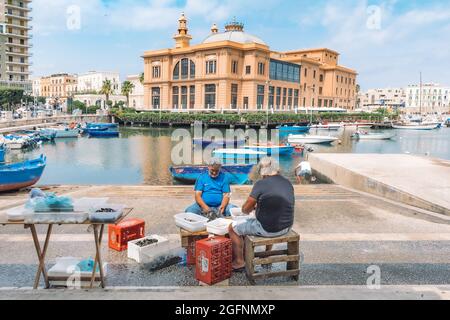 I pescatori locali lavano, puliscono e vendono frutta fresca di mare pronta a mangiare in un mercato di Street food all'aperto sul lungomare di Bari, Puglia, Italia Foto Stock