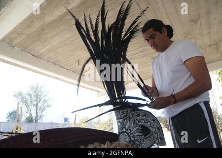 Non esclusiva: TEOTIHUACAN, MESSICO - AGOSTO 26: Un uomo mette le piume in un pennacchio prima vestito da guerriero azteco come parte di una cerimonia pre-ispanica Foto Stock