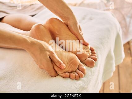 Massaggio plantare con olio da massaggio per donna mentre ci si rilassa e si riposa nella spa in vacanza Foto Stock