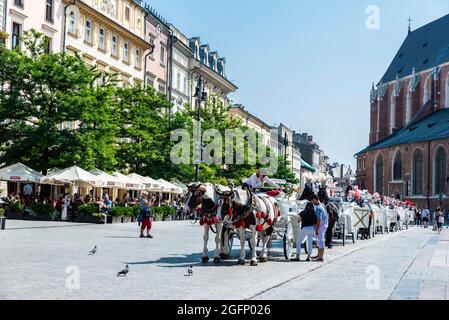 Cracovia, Polonia - 30 agosto 2018: Carrozza con cavalli che trasportano turisti sulla piazza principale del mercato o Rynek Głowny, strada dello shopping con ristoranti, Foto Stock