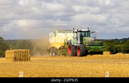 Trattore che tira una macchina per imballare e imballare la paglia in un campo. Hertfordshire. REGNO UNITO Foto Stock