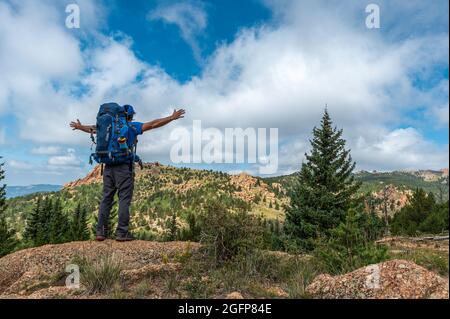 Backpacker tiene le braccia mentre si guarda nel paesaggio della Lost Creek Wilderness in Colorado Foto Stock