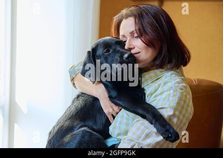 Ritratto di donna di mezza età e nero labrador cucciolo cane Foto Stock