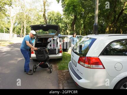 POZNAN, POLONIA - 11 giu 2016: Un uomo che carica un buggy bambino in un'automobile al parcheggio del parco Cytadela, Polonia Foto Stock