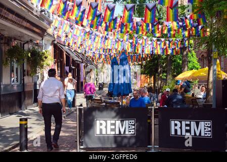 Le aziende locali decorano le loro facciate per prepararsi al Manchester Pride, il lungo evento LGBTQ+ che si svolge dal 27 al 30 agosto 2021. Gli organizzatori affermano che l'evento è stato il seguente: "Campagne per l'uguaglianza LGBTQ+, celebra la vita LGBTQ+ e crea opportunità che coinvolgono le persone LGBTQ+ nella Greater Manchester in modo che possano prosperare". Bandiere di orgoglio di progresso fuori del pub di Rembrandt su Canal Street nel villaggio gay. Foto Stock