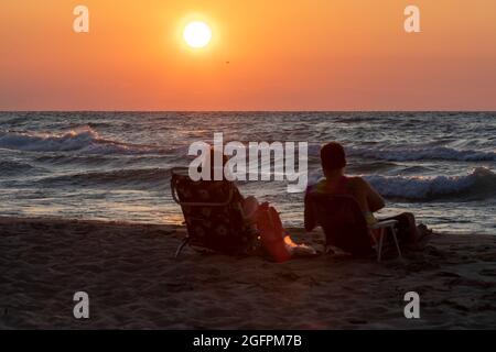 Union Pier, Michigan - una coppia guarda come il sole tramonta sul lago Michigan. Foto Stock