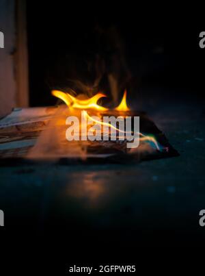 Primo piano la carta di vista che è bruciata sul terreno nel buio Foto Stock